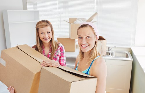 Professional movers carrying furniture through a South Kensington street